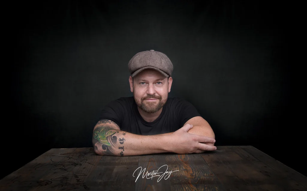 Morten Jay sitting at with arms crossed at table, looking at camera